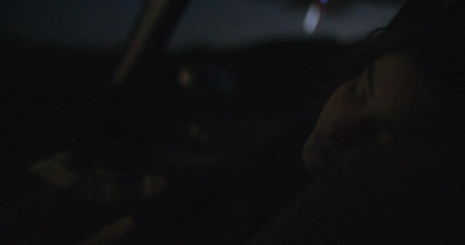 A woman sleeping in the front seat of a car while it travels at night