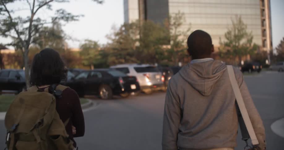 A man and woman walk through a parking lot