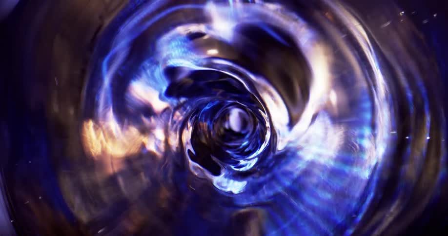 Quick spinning vortex of grayand electric blue fills tube lined with light and spots