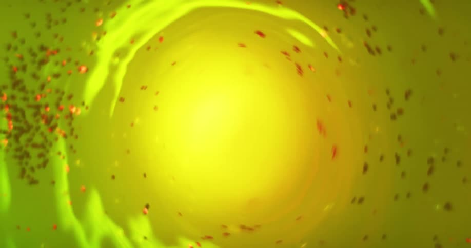 Yellow light shines illuminating a spinning surface with red particles caught in the vortex