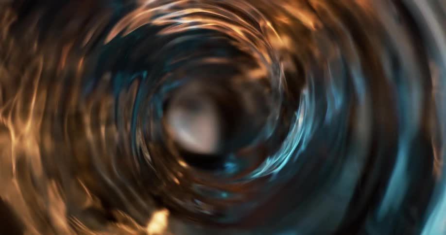 Top down close up of the interior of a blender spinning a spiral vortex of clear liquid