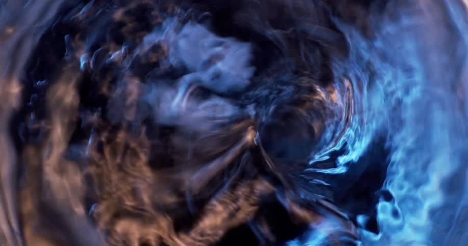 Colored lighting tints water as fluid churns and creates a whirlpool