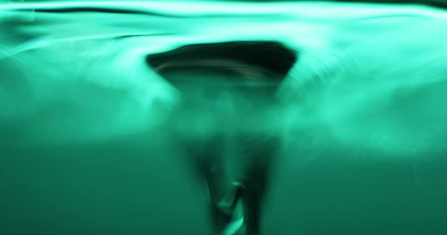 An object is moving in rough shaking water as light shines on the ripples above