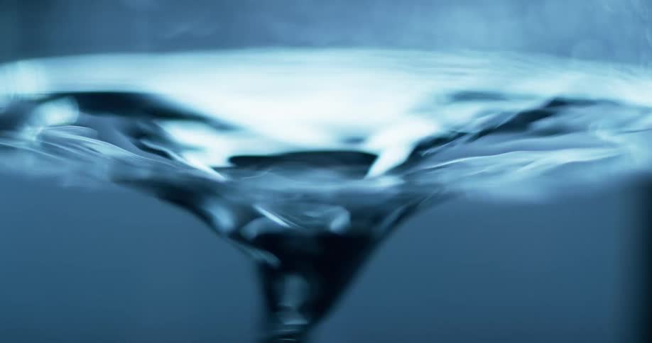 Light shines on water as it ripples and is being sucked down the drain