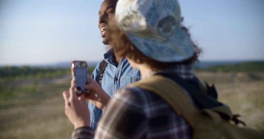 A woman uses her cellphone while laughing and talking with a man