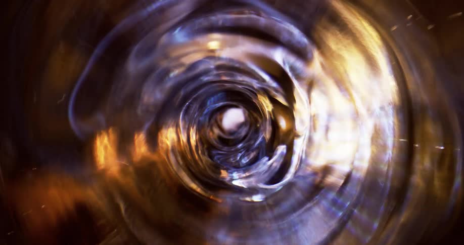 Top down close up of the interior of a blender spinning a spiral vortex of clear liquid