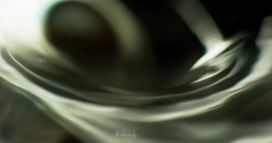 Looking into a swirling vortex as it spins and a ball spinning inside the liquid as it moves downward