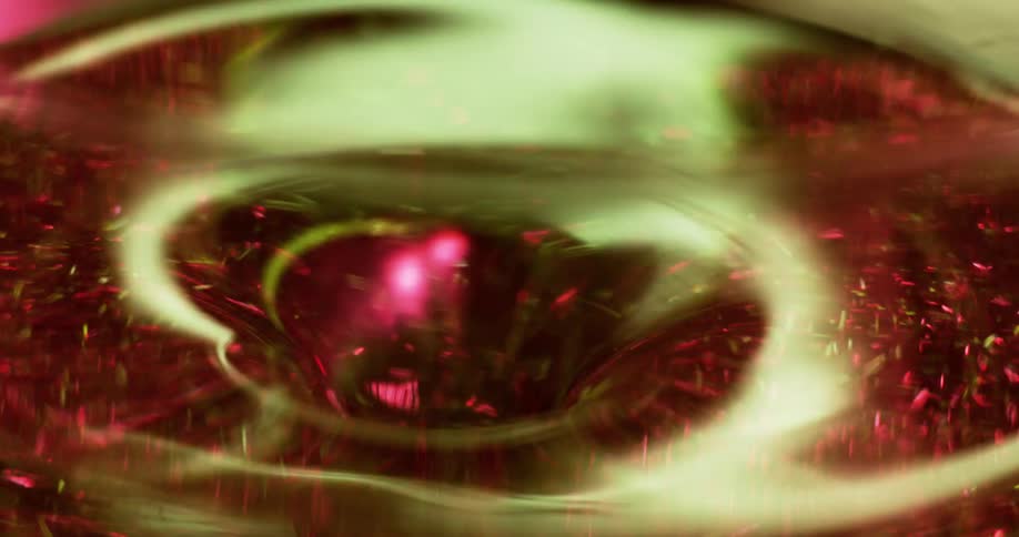 Green light shines on a swirling tunnel as red particles glow as they quickly move