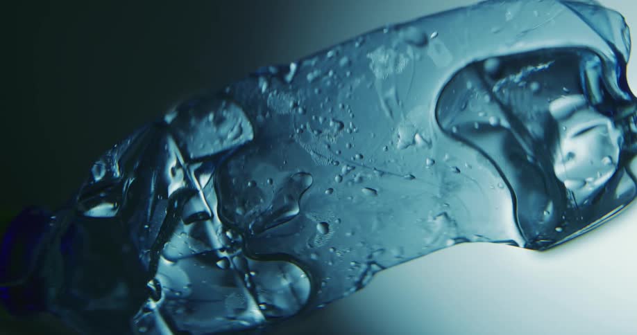 Light shines on a wet floating ice cube with water droplets on the surface