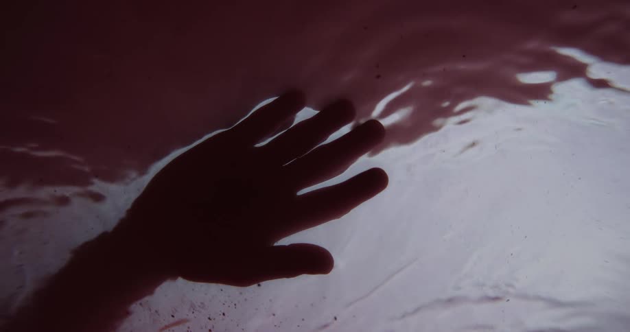 Water ripples as a person holds their hand over the surface of a stream of water