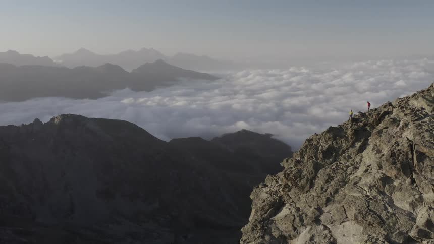 Two hikers stand overlooking misty valley in mountain range