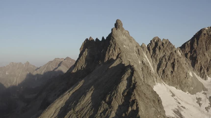 A jagged stone mountain peak under a clear daytime sky