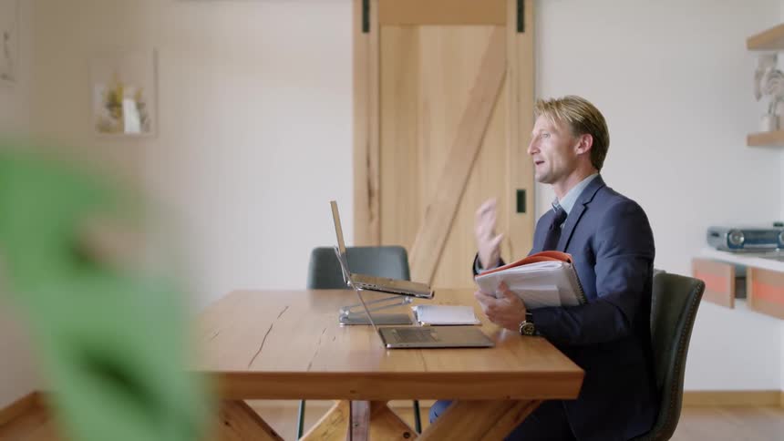 A man is talking to someone on a laptop in his office