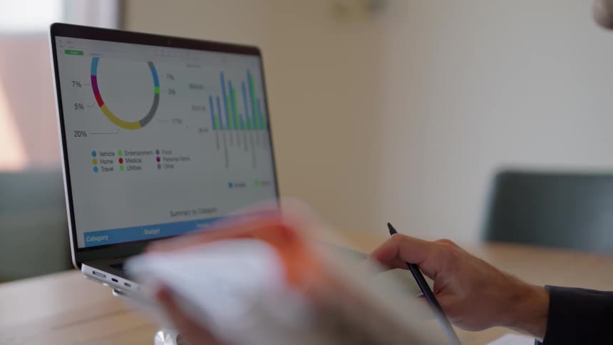 A person is taking notes from a budget on the computer