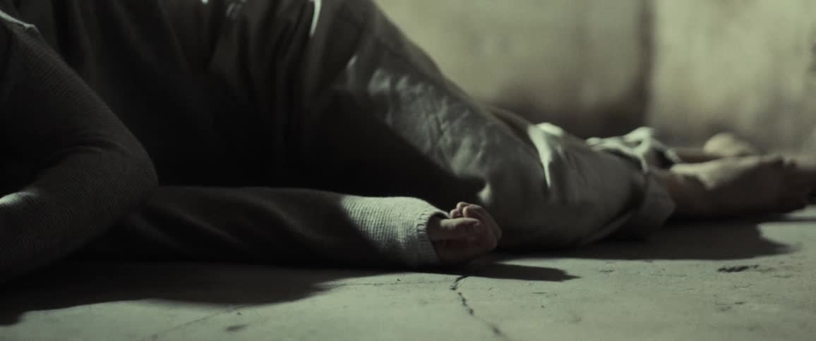 A woman lies on concrete and slowly wakes up