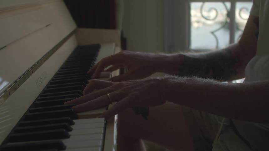 A man is playing the white piano