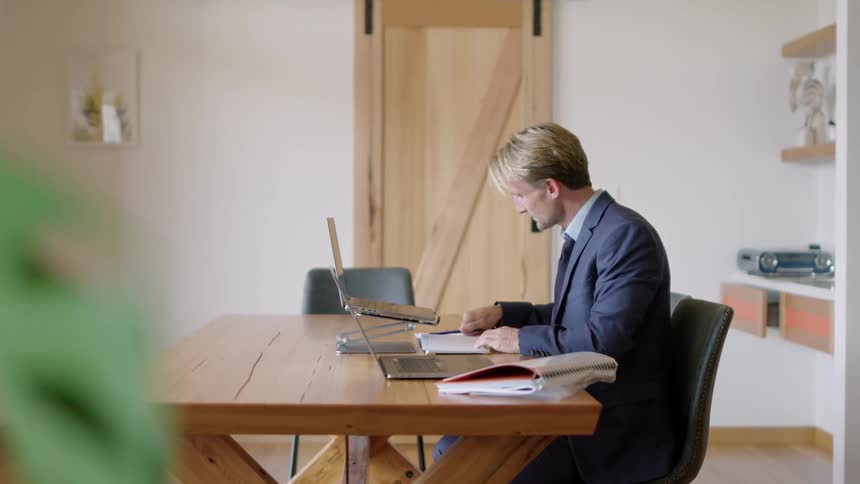 A man is sitting in his office and working on a laptop
