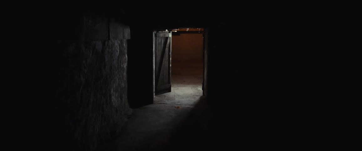 Ajar door lets light shine into dark rough walled room