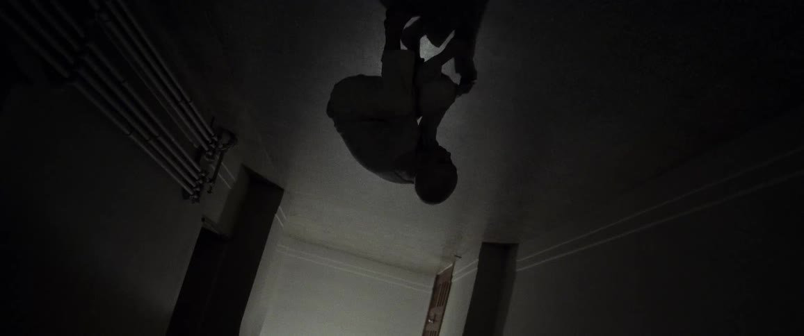 Upside down view of person silhouetted against light entering dim corridor standing from crouch