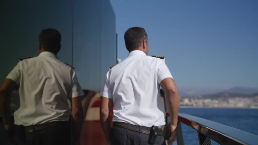 Man with sunglasses shirt and shorts walks onboard on a sunny day