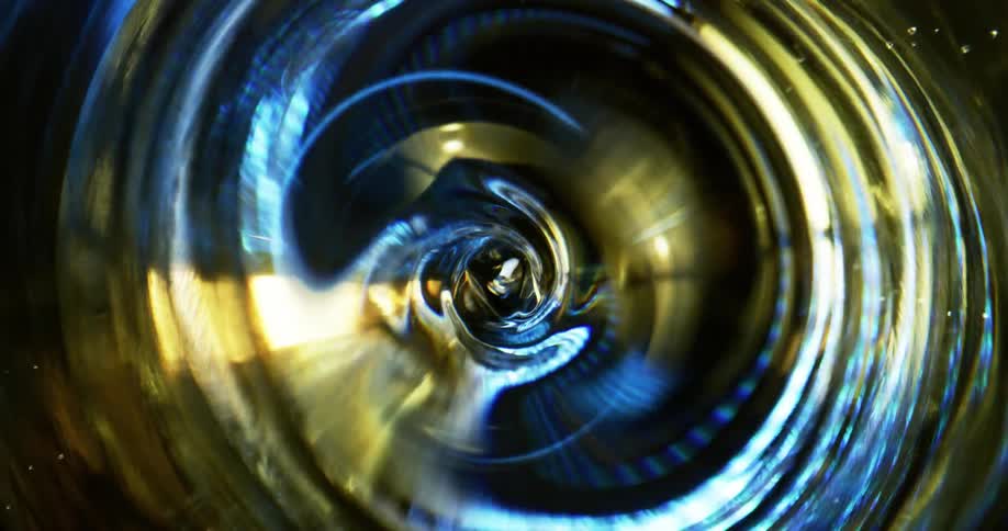 Liquid in a container spins and swirls reflecting light and color
