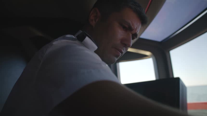 A man driving a boat concentrates as he looks at the dashboard