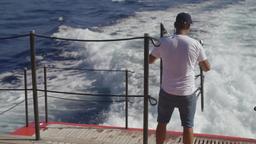 A man is setting equipment on a boat in the ocean