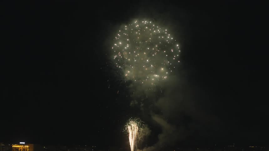 Fireworks explode in the night sky over a city
