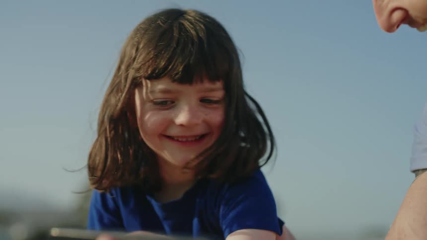 Father and daughter looks at smartphone talking and laughing