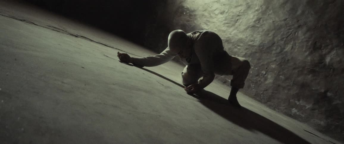 A woman is crawling on the floor in a cave