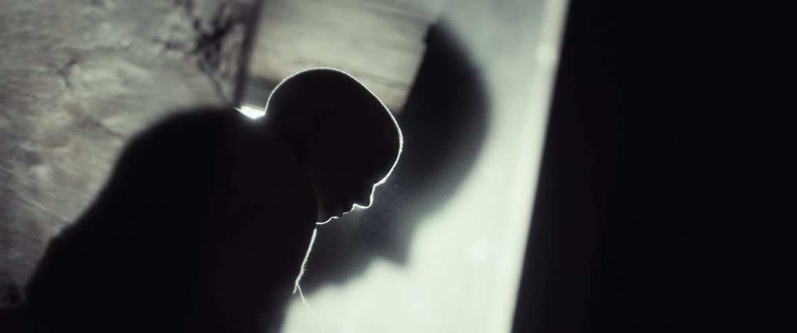 Silhouetted woman crouches beside mirror