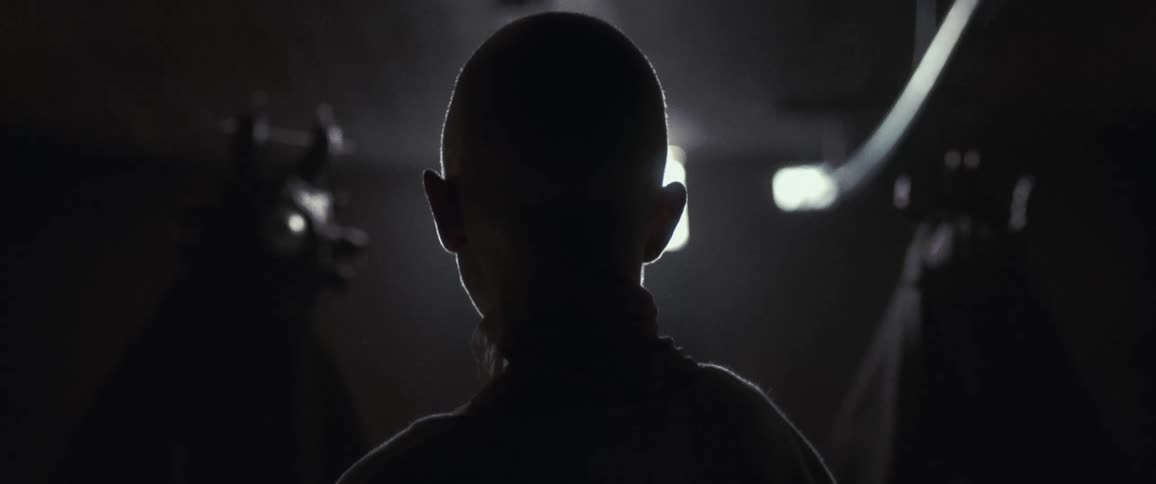 The back of a woman's head indoors with two shadowy figures