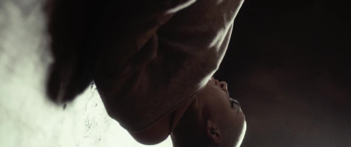 Woman with a shaved head moves close to surface casting a shadow