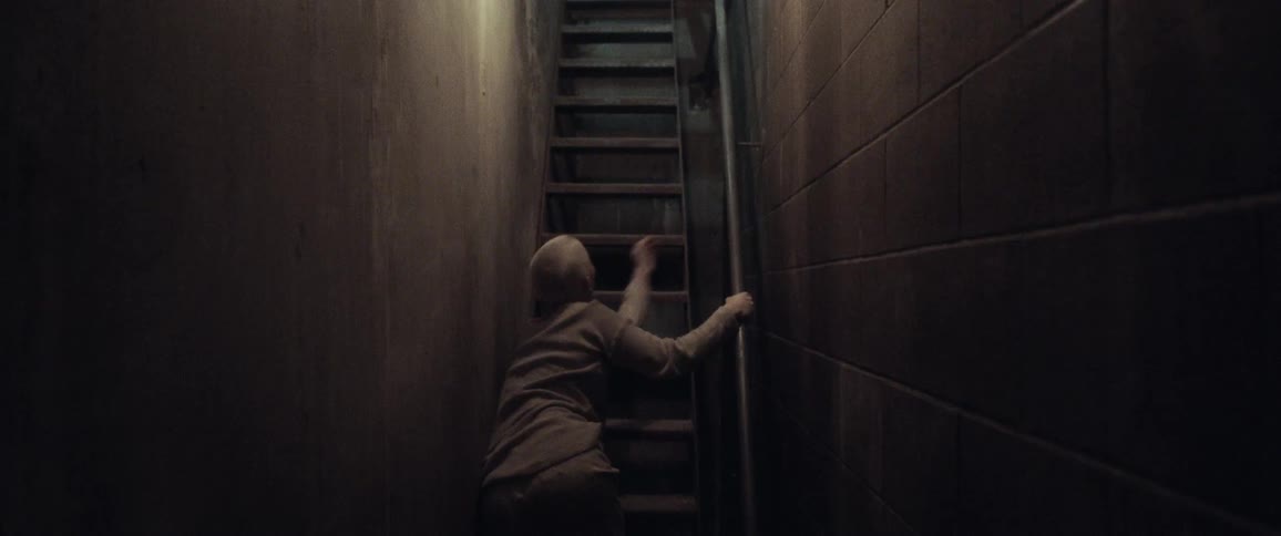Woman struggles up staircase in narrow corridor clinging to handrail