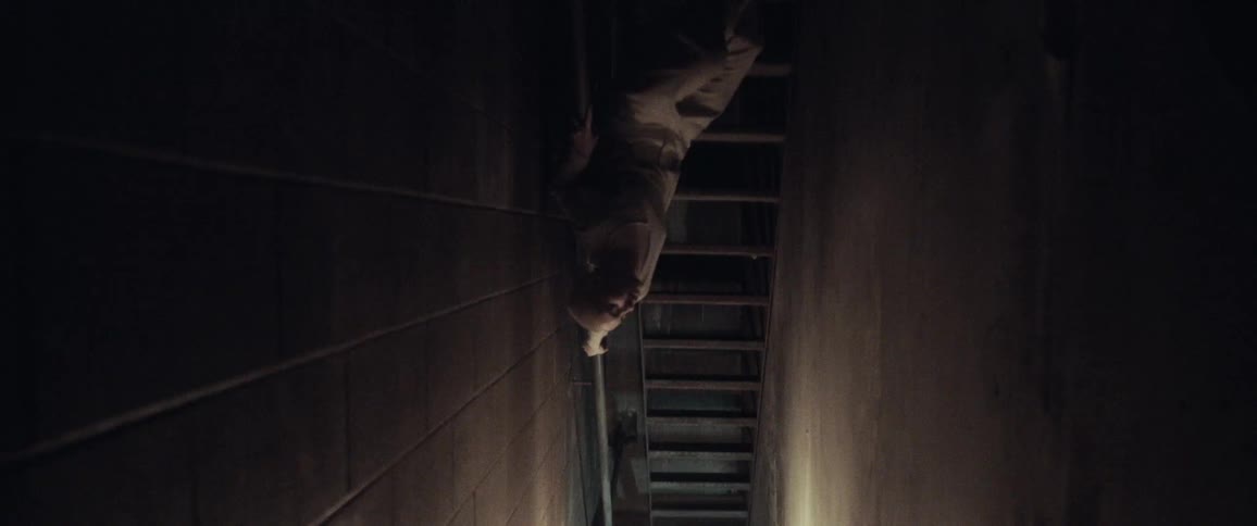 A person is crawling in a building near a staircase
