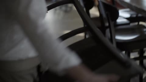 A woman pulls a chair from a bar and flips it over