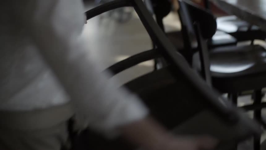 A woman pulls a chair from a bar and flips it over