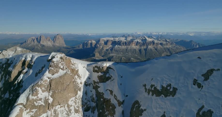 A mountain ridge covered in patches of snow under a clear daytime sky
