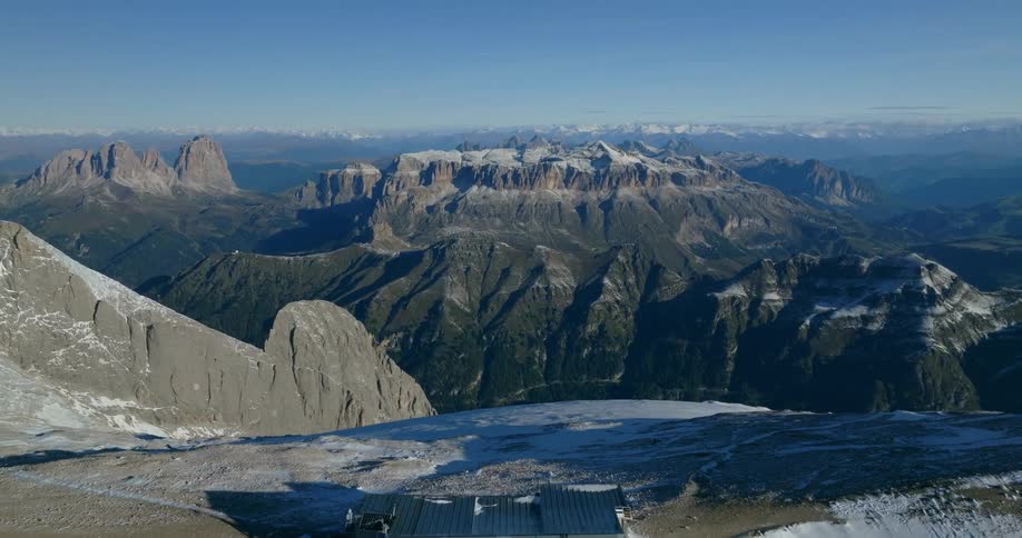 An aerial view of a mountain range with a small building on top