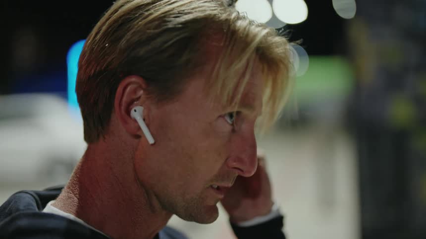 Man puts on earbuds preparing to jog in the city streets at night