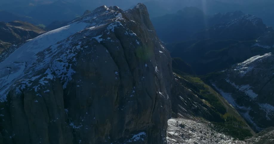 Snow covered mountain towers over valley with foggy mountains in the background