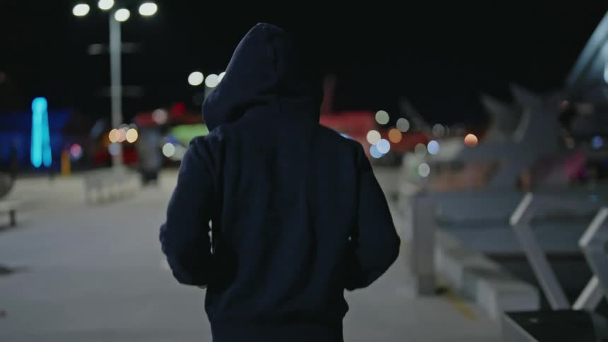 Jogger jogs near waterfront at night as nearby female pedestrian starts running too