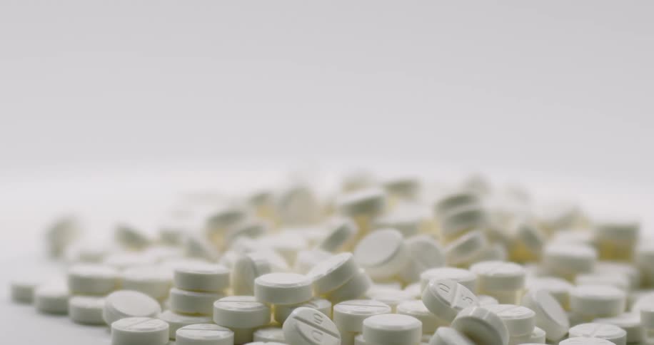 White round pills fall into a stack on a rotating surface