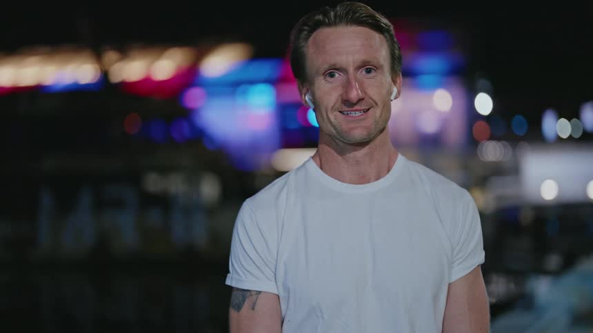Man stands on waterfront at night catching his breath
