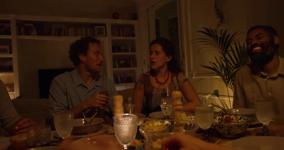 A group of friends sitting around a dinner table talking and laughing