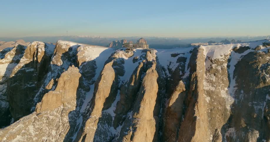 An aerial view of a mountain range with a small building on top