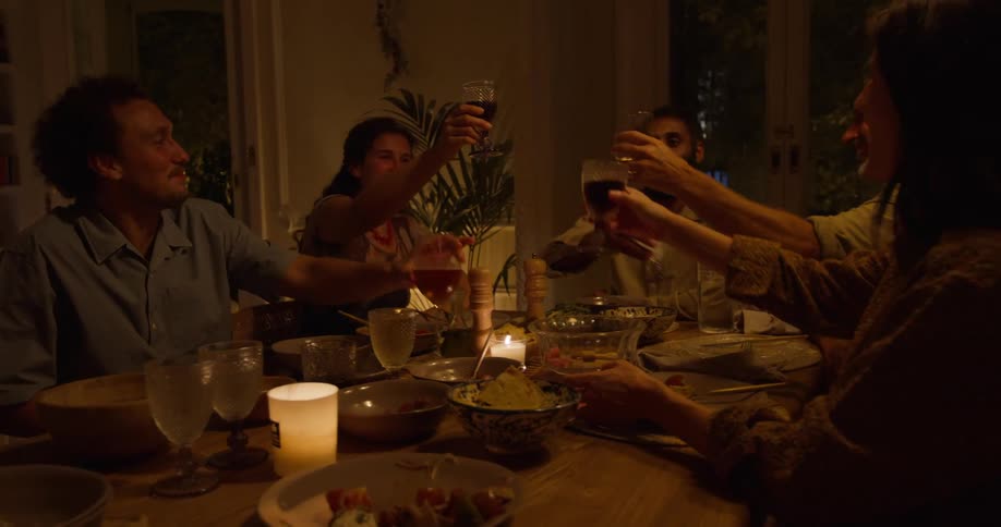A group of people toast their drinks at the dinner table