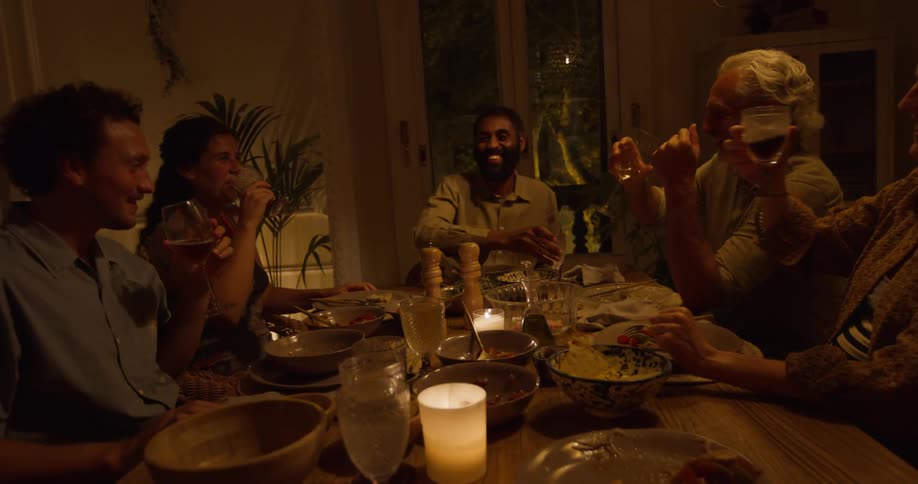 Friends toast then smile and talk at dinner party