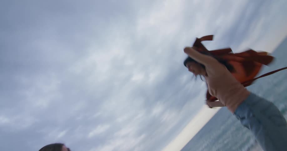 Two female friends standing on beach at end of tunnel pretend to be a bull and a matador