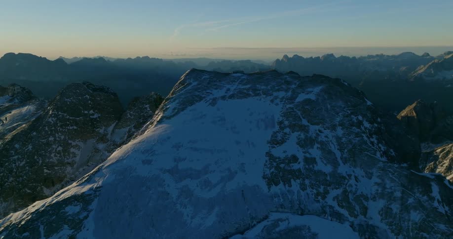 Aerial view of snowy mountain and mountain range at sunset